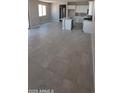 Bright living room with tile flooring flowing into an open kitchen featuring an island and modern appliances at 15593 S 180Th Ln, Goodyear, AZ 85338