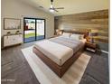 Stylish main bedroom featuring a modern accent wall, ceiling fan, and sliding glass door to backyard at 24811 W Wayland Dr, Buckeye, AZ 85326
