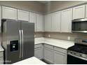 Updated kitchen featuring stainless steel appliances, gray cabinets, and white quartz countertops at 40816 W Sunland Dr, Maricopa, AZ 85138