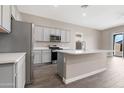 Spacious kitchen featuring stainless steel appliances, grey cabinets, and an island with a sink at 40816 W Sunland Dr, Maricopa, AZ 85138