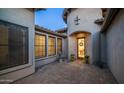 Private courtyard with a stone paver patio, arched doorway and windows, and decorative plants at 7841 E Stonecliff Cir, Mesa, AZ 85207