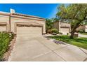 Beige home exterior showcasing a garage with beige doors, a concrete driveway and green grass at 8874 W Piute Ave, Peoria, AZ 85382