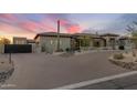 Elegant home exterior featuring a circular paver driveway, desert landscaping, and a gated entrance at 9456 E Sands Dr, Scottsdale, AZ 85255