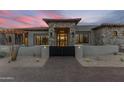 Inviting entrance with a stone facade, black gate, and desert landscaping, creating a grand arrival at 9456 E Sands Dr, Scottsdale, AZ 85255