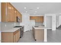 Modern kitchen with wooden cabinets, stainless steel appliances, a center island with seating, and a stylish tile backsplash at 10860 E Tiburon Ave, Mesa, AZ 85212
