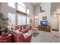 Bright living room featuring a high ceiling, large windows and a comfortable red leather sofa set at 4912 W Marco Polo Rd, Glendale, AZ 85308