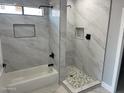 Modern bathroom features marble-look tile, stylish black fixtures, and a separate tub and shower at 5499 E Red Bird Ln, San Tan Valley, AZ 85140