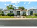 Charming single-story home with a red tile roof, lush landscaping, and a black trimmed window at 8196 E Sunnyside Dr, Scottsdale, AZ 85260