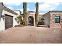 Elegant front entrance with stone archway, wrought iron gate, and meticulously maintained brick driveway at 13648 E Aloe Vera Dr, Scottsdale, AZ 85262