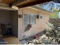 Exterior view of the side of the home with a window air conditioning unit and a boarded-up cat door at 2030 N 21St Pl, Phoenix, AZ 85006