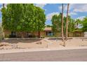 Inviting single-story home with desert landscaping, mature trees and a well-kept front yard at 2234 E Lawrence Rd, Phoenix, AZ 85016