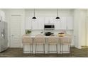 Contemporary kitchen featuring white cabinets, modern appliances, and a functional island with stylish bar stools at 32452 N Cherry St, San Tan Valley, AZ 85143