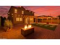 Stunning backyard featuring a fire pit, string lights, covered patio, and well-manicured artificial grass at 6632 W Saguaro Park Ln, Glendale, AZ 85310