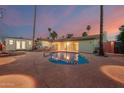 Backyard with a swimming pool, covered patio with outdoor seating, and tropical landscaping at dusk at 6932 E Latham St, Scottsdale, AZ 85257