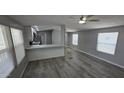 Open living space with gray plank floors, two windows, recessed lights, and kitchen with breakfast bar at 9632 E Arbor Cir, Mesa, AZ 85208