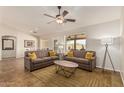Bright living room featuring tile floors, two sofas with yellow throw pillows, and a ceiling fan at 10940 E Olla Ave, Mesa, AZ 85212