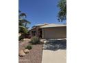 Single-story home with a two-car garage, desert landscaping, and walkway leading to the front door at 13280 W Caribbean Ln, Surprise, AZ 85379