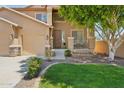 Inviting home with manicured lawn, mature tree, and charming front porch at 13724 W Luke Ave, Litchfield Park, AZ 85340