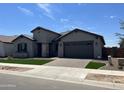Attractive single-story house with a two-car garage, stone accents, and well-maintained landscaping at 16035 W Questa Dr, Surprise, AZ 85387