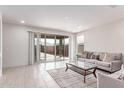 Bright living room featuring neutral walls, tile flooring, and sliding glass doors that open to the backyard at 16221 W Prickly Pear Trl, Surprise, AZ 85387