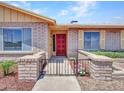 Close-up of a charming home's entrance with a red front door, brick accents, and a well-kept garden at 13810 N 39Th Ave, Phoenix, AZ 85053