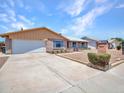 Inviting single-story home with a well-maintained lawn, concrete driveway, and charming brick accents under a sunny sky at 13810 N 39Th Ave, Phoenix, AZ 85053