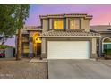 Inviting two-story home with a spacious garage, desert landscaping, and warm exterior lighting at 1655 W Stanford Ave, Gilbert, AZ 85233