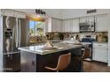 Well-lit kitchen features granite countertops, stainless steel appliances and a central island with seating at 4220 E San Angelo Ave, Gilbert, AZ 85234