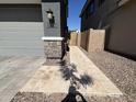 Side view of a gray two-story home with stone accents and a paved walkway leading to a wooden gate at 4490 S Montana Dr, Chandler, AZ 85248