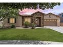 Inviting single-story home with stone details, lush green lawn, and a convenient two-car garage at 6299 S Roanoke St, Gilbert, AZ 85298