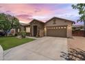 Beautiful single-story home with stone accents, a well-kept lawn, and a two-car garage in the evening at 6299 S Roanoke St, Gilbert, AZ 85298