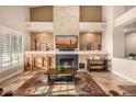 Open-concept living room with a fireplace, large windows, and a decorative rug at 11124 N 138Th Way, Scottsdale, AZ 85259