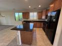 Kitchen with wood cabinets, black appliances, granite countertops, island, and tile flooring at 26747 W Pontiac Dr, Buckeye, AZ 85396