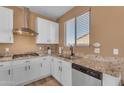 Bright kitchen featuring white cabinets, granite countertops, and stainless steel hood at 40657 W Somers Dr, Maricopa, AZ 85138