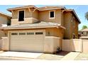 Spacious two-car garage door, enhanced by tan stucco exterior and modern lighting fixtures at 5840 E Holmes Ave, Mesa, AZ 85206