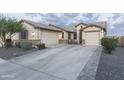 Long driveway leading to a home with attached garages and neutral desert landscaping at 18493 W Hiddenview Dr, Goodyear, AZ 85338