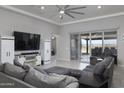 Open living room with fan, TV, and sliding doors leading to the outdoor covered patio at 18493 W Hiddenview Dr, Goodyear, AZ 85338