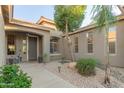 Inviting front entry with decorative plants, lanterns, and a desert landscape, complete with accent lighting and a palm tree at 3523 W Buckhorn Trl, Phoenix, AZ 85083