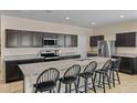 Stylish kitchen featuring dark cabinets, granite countertops, and a spacious island with seating at 36412 W Pampoloma Ave, Maricopa, AZ 85138