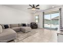 Bright living room with modern sectional couch, tile flooring, and backyard access at 39985 W Rio Lobo Dr, Maricopa, AZ 85138