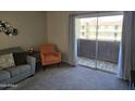 Cozy living room featuring a sofa and orange chair, offering a view of the outdoor building from the balcony at 461 W Holmes Ave # 360, Mesa, AZ 85210