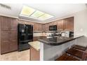 Modern kitchen featuring dark wood cabinets, granite countertops, and stainless steel appliances under a skylight at 650 E Silver Creek Rd, Gilbert, AZ 85296