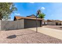 View of the side of the house with a gray brick garage, basketball hoop and low maintenance rock landscaping at 6751 W Cameron Dr, Peoria, AZ 85345