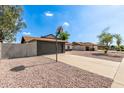 View of the side of the house with a gray brick garage, basketball hoop and low maintenance rock landscaping at 6751 W Cameron Dr, Peoria, AZ 85345