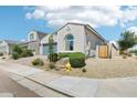 Lovely one-story home showcasing well-maintained landscaping, desert rock, and a blue two car garage door at 1865 N 141St Ave, Goodyear, AZ 85395
