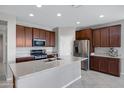 Spacious kitchen features stainless steel appliances, dark wood cabinetry, granite countertops, and large center island at 25974 W Horsham Dr, Buckeye, AZ 85396