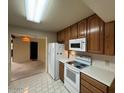 Functional kitchen with white appliances, wooden cabinetry, and tiled flooring at 4602 N 50Th Ave, Phoenix, AZ 85031