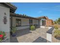 Inviting covered porch with brick flooring, offering a cozy outdoor seating area with charming plants and decor at 530 W Almeria Rd, Phoenix, AZ 85003