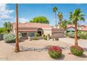 Inviting single-story home with desert landscaping, rocks, mature palm trees, and a two-car garage at 8977 E Ludlow Dr, Scottsdale, AZ 85260
