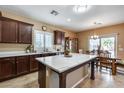 Open kitchen with dark wood cabinets, quartz countertop island with dining area, and lots of natural light at 9952 W Jessie Ln, Peoria, AZ 85383